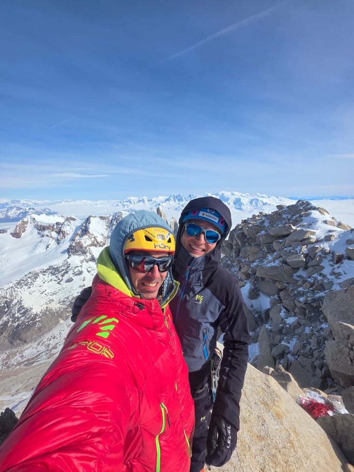 Two climbers smile on the summit of Fitz Roy in winter.