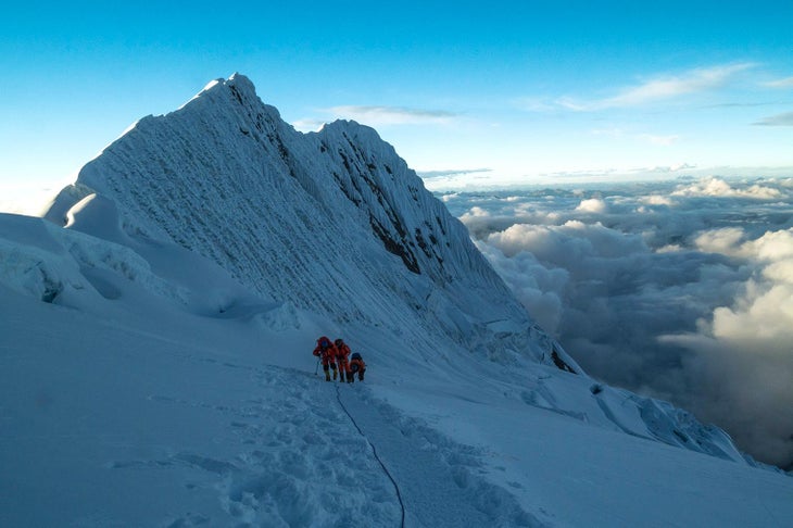 three climbers ascending a snowy mountain in nepal